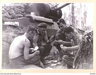 BOUGAINVILLE. 1945-05-21. A TANK CREW FROM B SQUADRON, 2/4 ARMOURED REGIMENT, SETTLING DOWN TO A GAME OF CARDS WHILE AWAITING THE MOVE FORWARD TO CONSOLIDATE C COMPANY, 24 INFANTRY BATTALION ..