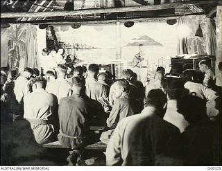 PORT MORESBY, PAPUA. C. 1942-12. AIRMEN OF NO. 30 (BEAUFIGHTER) SQUADRON RAAF ENJOY SINGING CHRISTMAS CAROLS IN A NATIVE-STYLE HUT IN THE JUNGLE