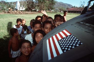 Samoan children gather near a 53rd Aviation Battalion UH-60 Black Hawk helicopter on the island of Upolu. The helicopter is delivering supplies as part of U.S. military disaster relief efforts in the aftermath of Cyclone Ofa