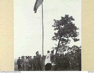 DUMPU, NEW GUINEA. 1944-02-06. THE FLAG BEING HOISTED TO FULL MAST AFTER THE SOUNDING OF "REVEILLE", DURING A DEDICATION SERVICE AT THE DUMPU WAR CEMETERY. THE SERVICE WAS JOINTLY CONDUCTED BY ..