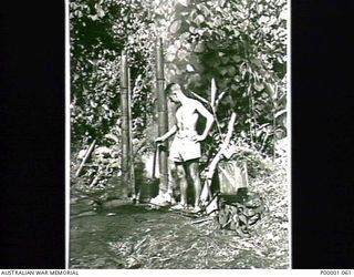 THE SOLOMON ISLANDS, 1945-02-26. A SERVICEMAN POSHES HIS CLOTHES BEING WASHED AT HIS CAMP ON BOUGAINVILLE ISLAND. (RNZAF OFFICIAL PHOTOGRAPH.)