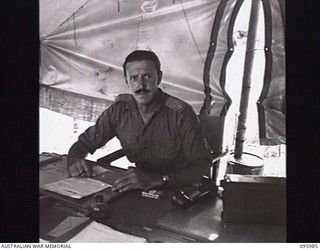 CAPE WOM, WEWAK AREA, NEW GUINEA. 1945-09-01. MAJOR T. FOGARTY, G11, HEADQUARTERS 6 DIVISION AT HIS DESK