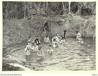 BOUGAINVILLE ISLAND, 1945-01-20. TROOPS OF "A" COMPANY, 42ND INFANTRY BATTALION WASHING THEMSELVES IN A WATER FILLED BOMB CRATER AFTER OCCUPYING THE VILLAGE OF MAWARAKA. IDENTIFIED PERSONNEL ARE:- ..