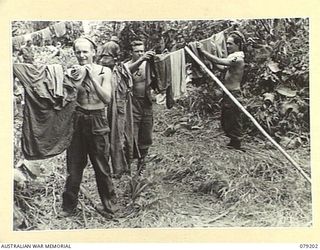 BOUGAINVILLE ISLAND. 1945-02-17. TROOPS OF D COMPANY, 9TH INFANTRY BATTALION HANGING THEIR WASHING OUT ACROSS THE MOSIGETTA ROAD AT ONE OF THE UNIT FORWARD POSITIONS. IDENTIFIED PERSONNEL ARE:- ..