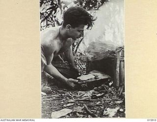 1943-10-02. NEW GUINEA. MARKHAM VALLEY. OLD MUNUM. PTE. A. COCKBURN OF FIVE DOCK, N.S.W. WITH AN IMPROVISED STOVE MADE FROM A DEHYDRATED MUTTON TIN. HE IS ABOUT TO COOK A THREE MINUTE DAMPER. ..