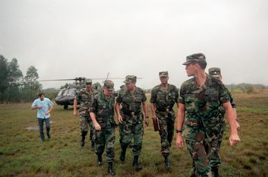 GEN Colin Powell, center, Chairman of the Joint Chiefs of STAFF, talks to an officer after disembarking from a UH-60A Black Hawk helicopter to visit troops in the field. MGEN Fred A. Gorden, Commanding General, 25th Infantry Division (Light), walks on Powell's left