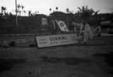 Guam, Harrison Forman, the photographer, next to a sign for 'Guam, Military Installation'