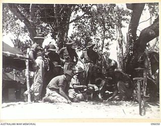 WIRUI BEACH, WEWAK AREA, NEW GUINEA. 1945-08-25. A MECHANIC DESCRIBES TO 2/11 INFANTRY BATTALION DETAILS OF A CAPTURED JAPANESE LIGHTING PLANT. THE UNIT IS LOCATED ON THE BEACH SINCE COMING OUT OF ..