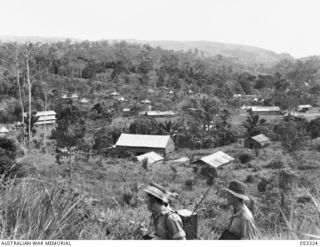 SOGERI VALLEY, NEW GUINEA. 1943-06-26. NEW GUINEA FORCE SCHOOL OF SIGNALS CAMP, SHOWING MEN'S HUTS, CLASSROOMS, TWO STOREY SLEEPING HUTS AND TENTS. IN THE FOREGROUND, VX135722 WARRANT OFFICER 2 J. ..