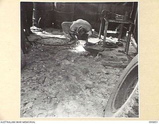 CAPE WOM, WEWAK AREA, NEW GUINEA. 1945-08-30. CRAFTSMAN J. MANNS, 2/42 LIGHT AID DETACHMENT, CORPS OF AUSTRALIAN ELECTRICAL AND MECHANICAL ENGINEERS, USING AN ELECTRIC WELDER