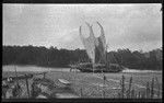 Large lakatoi canoe with people on board, on mudflat