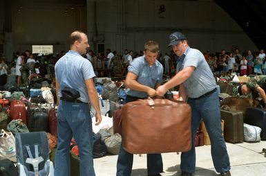 Sailors from U.S. Naval Station, Guam, move luggage at a temporary evacuation center during Operation Fiery Vigil. The center was set up to process military dependents who were evacuated from the Philippines after volcanic ash from the eruption of Mount Pinatubo disrupted operations at Clark Air Base and Naval Station, Subic Bay.