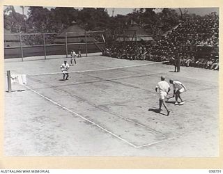 TOROKINA, BOUGAINVILLE. 1945-11-17. A GENERAL VIEW OF THE TENNIS COURT DURING A DOUBLES TENNIS EXHIBITION MATCH PLAYED AT 28 LINES OF COMMUNICATION AREA SALVAGE UNIT, HEADQUARTERS 3 DIVISION. THE ..