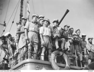 AT SEA, OFF BUIN, BOUGAINVILLE, 1945-08-20. MEMBERS OF THE CREW OF THE CORVETTE HMAS LITHGOW WATCHING FROM THE GUN DECK DURING THE INTERROGATION OF A JAPANESE ENVOY FROM LIEUTENANT-GENERAL M. ..