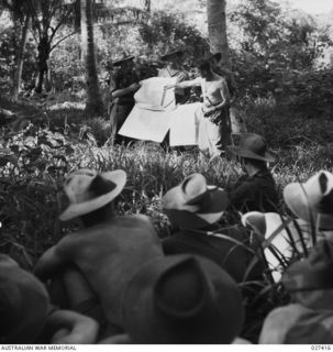 WANIGELA, NEW GUINEA. 1942-10. TROOPS OF THE 2/6TH AUSTRALIAN INDEPENDENT COMPANY BEING GIVEN FINAL BATTLE ORDERS BY THEIR COMMANDING OFFICER, MAJOR H.G. HARCOURT, DSO., MC., (WITHOUT SHIRT). LT. ..