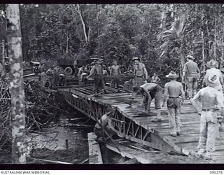 BOUGAINVILLE. 1945-03-30. ENGINEERS OF 15 FIELD COMPANY ROYAL AUSTRALIAN ENGINEERS LAYING A GIRDER ON A 24 TON BOX GIRDER BRIDGE OVER COOMBES CROSSING, ON THE TOKO-DARARA ROAD, TO ALLOW MATILDA ..