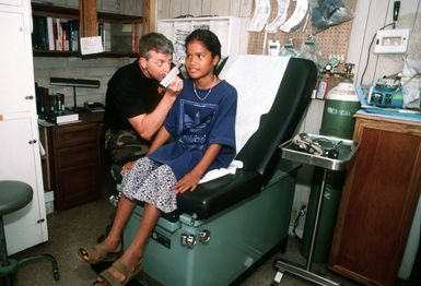 MASTER SGT. Paul "Doc" Armistead, a medical technician from Eglin Air Force Base, Fla. checks the ears of Inaria Pulusou, a Chuukese girl. SGT. Armistead is a member of a thirteen man civic-action team, on 8-months temporary duty, and chartered to enhance the socio-economic development of Chuuk, while providing a U.S. military presence at this island 632 miles southeast of Guam. Exact Date Shot Unknown . Published in AIRMAN Magazine August 1997