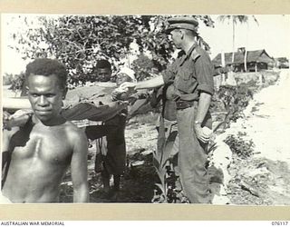 MILILAT, NEW GUINEA. 1944-09-21. MR. R.G. SCOTT, AUSTRALIAN RED CROSS SOCIETY ATTACHED TO HEADQUARTERS 5TH DIVISION, HANDS A WOUNDED NATIVE A PACKET OF CIGARETTES AS HE ARRIVES AT THE AUSTRALIAN ..