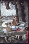 Domestic scene: child washes dishes in a basin on house veranda