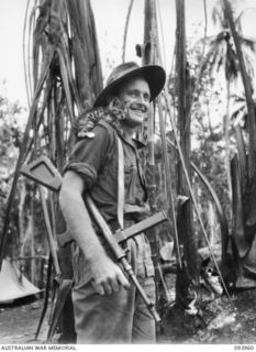 ULUPU, NEW GUINEA, 1945-07-10. SIGNALMAN H.G. GLADSTONE, B COMPANY, 2/5 INFANTRY BATTALION WITH HIS KITTEN "TIGER". HE FOUND THE KITTEN IN A DESERTED VILLAGE AT MALBA AND IT IS CONTENT TO RIDE ON ..