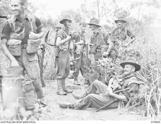 BUT AREA, NEW GUINEA. 1945-03-17. MEMBERS OF THE 2/2ND INFANTRY BATTALION DURING A REST PAUSE BEFORE CROSSING THE NINAHAU RIVER. NX69030 CORPORAL R.L. SMITH (2), MAINTAINS RADIO CONTACT. IDENTIFIED ..