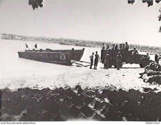 NEAR MAMAGOTA, SOUTH BOUGAINVILLE. 1945. LANDING CRAFT VEHICLE AND OPERATOR AT BEACH WITH A TRUCKLOAD OF MEN. (DONOR A. BARING)