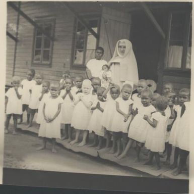 Nun with a group of children at Vunapope Catholic Mission, Kokopo, near Rabaul, New Guinea, ca.1936 / Sarah Chinnery