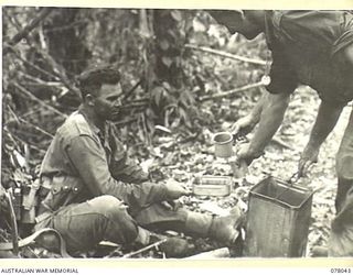 BOUGAINVILLE ISLAND. 1944-12-30. QX37473 STAFF SERGEANT R.C. KEATES (2) SERVING A DRINK OF TEA TO N346207 PRIVATE E.A. GOTTS (1) DURING THE ATTACK ON JAPANESE POSITIONS IN THE PIATERAPAIA SECTOR BY ..
