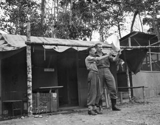 NADZAB, NEW GUINEA. 1944-05-09. SERGEANT A. R. B. SMITH, MANLY, NSW, THE UNIT'S X-RAY TECHNICIAN, SHOWS SQUADRON LEADER ADRIAN MCGLYNN, SYDNEY, NSW, COMMANDING OFFICER, NO. 23 MEDICAL CLEARING ..