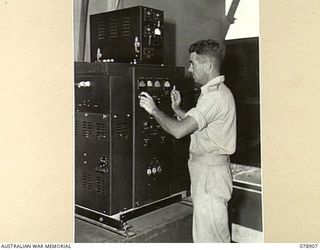 LAE AREA, NEW GUINEA. 1945-02-06. NX82183 LIEUTENANT M.J. DUNNE, OFFICER IN CHARGE, 18TH WIRELESS SECTION (HEAVY) INSPECTING ONE OF THE BC610-E, 500 WATT TRANSMITTERS BEING INSTALLED IN THE SIGNALS ..