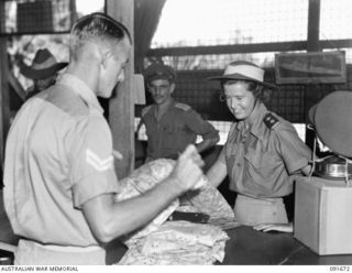 TOROKINA, BOUGAINVILLE. 1945-05-07. LIEUTENANT K. CLAYTON, AUSTRALIAN ARMY NURSING SERVICE, 2/1 GENERAL HOSPITAL (1), MAKES A PURCHASE FROM CORPORAL S.G. BOWDEN (2), AT 4 SECTION OFFICERS' SHOP