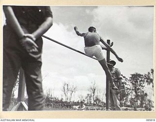 WONDECLA AREA, QLD. 1945-01-19. LIEUTENANT DOUGLAS, HQ 20 INFANTRY BRIGADE, CLEARING THE BAR AT 5 FEET 4 INCHES DURING THE 9 DIVISION GYMKHANA AND RACE MEETING HELD AT HERBERTON RACECOURSE