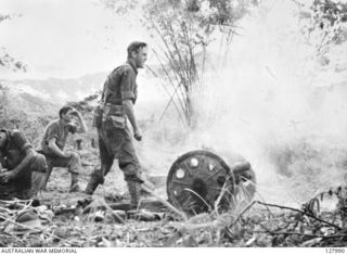 NX12463 LIEUTENANT R. H. DAWSON OF THE 2/6TH AUSTRALIAN FIELD REGIMENT, FIRING A CAPTURED MOUNTAIN GUN ONTO THE JAPANESE IN THE "COCONUTS" IN THE BOBDUBI AREA, NEW GUINEA, 1943-07-30, WATCHED BY A ..