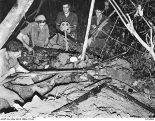 1943-09-14. NEW GUINEA. KOMIATUM RIDGE. IN THEIR HURRIED RETREAT FROM KOMIATUM RIDGE THE JAPANESE LEFT BEHIND WHAT FOR THEM WAS A CONSIDERABLE AMOUNT OF EQUIPMENT. PTE. LES. HARGREAVES OF BELLEVUE ..