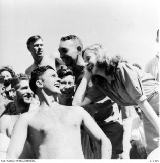 New Guinea. December 1943. Kitty Bluett who toured with Gladys Moncrieff's concert party entertaining the troops, leans on an appreciative and stalwart shoulder