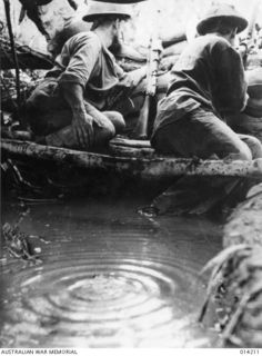 1943-01-25. PAPUA. SANANANDA AREA. MEN OF 2/7TH CAVALRY REGIMENT IN A FOX HOLE, A FORWARD SECTION POST LESS THAN 30 YARDS FROM JAPANESE POSITIONS, SURROUNDED BY MUD AND WATER. THE PHOTOGRAPHER WHO ..