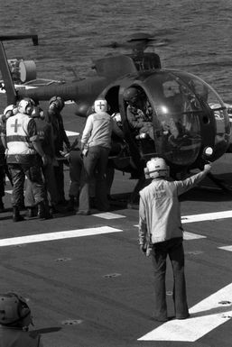 Flight deck crewmen and medical personnel remove a wounded serviceman from a US Army OH-6A Cayuse helicopter on the flight deck of the amphibious assault ship USS GUAM (LPH 9). The serviceman was wounded during the multiservice, multinational Operation URGENT FURY