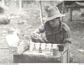 MALMAL MISSION, JACQUINOT BAY, NEW BRITAIN. 1944-11-30. QX49687 CORPORAL R. TAYLOR, HEADQUARTERS, 5TH DIVISION, CONDUCTING A HORROCKS TEST ON WATER SAMPLES DRAWN FROM THE AREA. THIS TEST IS USED TO ..