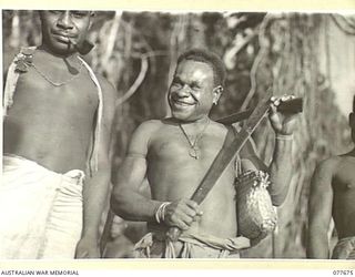 JACQUINOT BAY, NEW BRITAIN. 1944-12-13. AUSTRALIAN NEW GUINEA ADMINISTRATIVE UNIT NATIVES WAITING ON THE BEACH FOR THE BARGE TO TAKE THEM ACROSS THE BAY TO THE 5TH DIVISION AREA