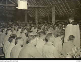 MADANG, NEW GUINEA. 1944-12-25. RAAF CHAPLAIN R. CLARK, FORMERLY OF ST ANDREWS CHURCH OF ENGLAND, BRIGHTON, VIC, CONDUCTING A COMBINED SERVICE IN THE RAAF MEMORIAL CHAPEL NEW GUINEA ON CHRISTMAS ..