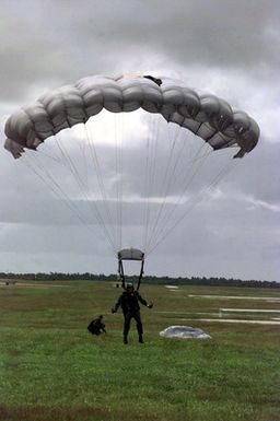 Straight on medium shot of US Marine GUNNERY Sergeant Elder, Platoon Sergeant, 2nd Platoon, Company A, 5th Force Reconnaissance Battalion, 3rd Marines, lands safely with his MC5 Freefall Square Parachute after completing a 9-thousand foot combat jump from a USAF C-130 Hercules aircraft (Not shown) during Force Reconnaissance Exercises at Andersen Air Force Base, Guam