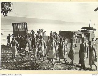 JACQUINOT BAY, NEW BRITAIN. 1944-12-13. AUSTRALIAN NEW GUINEA ADMINISTRATIVE UNIT NATIVES BOARDING THE BARGE WHICH IS TO TAKE THEM ACROSS THE BAY TO THE 5TH DIVISION AREA