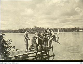 MADANG, NEW GUINEA. C. 1944-12. WHETHER SHE LIKES IT OR NOT THIS NURSE AT A MEDICAL RECEIVING STATION IS GOING TO GET WET AS SHE IS THROWN FROM A JETTY INTO THE WATER BY RAAF MEMBERS