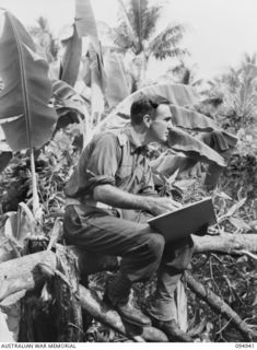 CAPE WOM, WEWAK AREA, NEW GUINEA. 1945-08-07. LIEUTENANT E.J. WOOD, OFFICER- IN- CHARGE AMMUNITION DISTRIBUTION (2), INDICATING TO CAPTAIN W.N. MORRISON, OFFICER- IN- CHARGE OF SUPPLY DISTRIBUTION ..