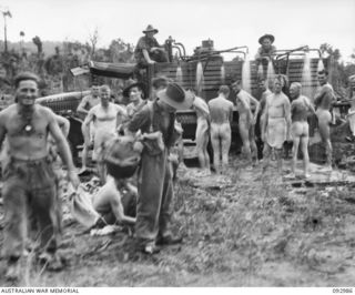 BORAM AREA, NEW GUINEA, 1945-06-07. MEMBERS OF 2/3 INFANTRY BATTALION TAKING SHOWERS FROM A MOBILE SHOWER UNIT. IDENTIFIED PERSONNEL ARE:- PRIVATE L.G. DAVIDSON (1); SERGEANT H.M. PEARN (2); ..