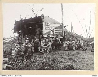 BERRY'S HILL, CENTRAL BOUGAINVILLE, 1945-06-27. THE YMCA - AUSTRALIAN COMFORTS FUND TEA POINT ON BERRY'S HILL. SHOWN ARE MEMBERS OF 7 INFANTRY BATTALION HAVING A CUP OF TEA. A HUNDRED GALLONS OF ..