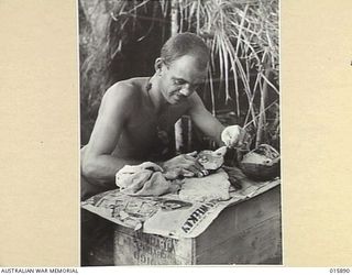 1943-10-01. NEW GUINEA. MARKHAM VALLEY. OLD MUNUM. SIG. L. DAVEY OF WANGARATTA, VIC., MAKES JUNGLE DAMPER. HE USES A CUSTARD TIN ROLLER, COCONUT SHELL FLOUR-SIFTER AND CRUSHED BISCUITS FOR FLOUR. ..