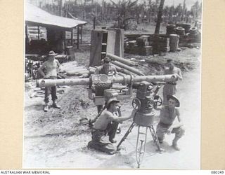 HANSA BAY, NEW GUINEA. 1944-07-10. MEMBERS OF THE 5TH DIVISION SALVAGE GROUP EXAMINE AN ABANDONED JAPANESE 75MM ANTI-AIRCRAFT RANGE AND HEIGHT FINDER. THE INSTRUMENT, SALVAGED FROM THE SEA, HAS ..