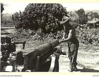 BOUGAINVILLE ISLAND, 1944-11-17. VX83213 CRAFTSMAN C.H. EVANS, 4TH FIELD REGIMENT, CLEANING THE BORE OF A 25 POUNDER IN THE UNIT GUN PARK