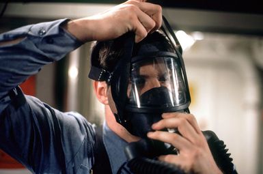 A member of a firefighting team dons oxygen breathing apparatus before taking part in a drill aboard the amphibous assault ship USS GUAM (LPH 9)